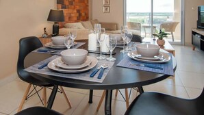 A dining area with a round table set for four, surrounded by black chairs.
