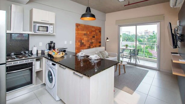 A compact kitchen with a central island, a washing machine, a microwave, and a dining area with a view.