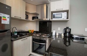 Une cuisine moderne équipée d’un réfrigérateur en acier inoxydable, d’un four à micro-ondes, d’une cuisinière et d’une machine à café.