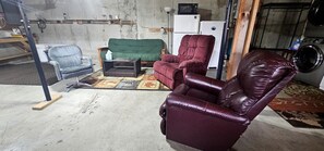 Ein Zimmer mit einem grünen Sofa, einem roten Ledersessel, einem blauen Sessel und einem kleinen Tisch mit einer Taschentuchbox.