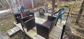 Eine Terrasse mit Korbmöbeln, einem Heizstrahler und einer Feuerstelle.