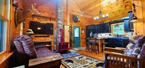 Ein Blockhaus-Interieur mit Kamin, Fernseher, Küchenzeile und aufgehängten Tierköpfen.