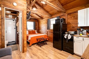 Acogedora habitación estilo cabaña con cama, refrigerador, lavamanos y ventana.