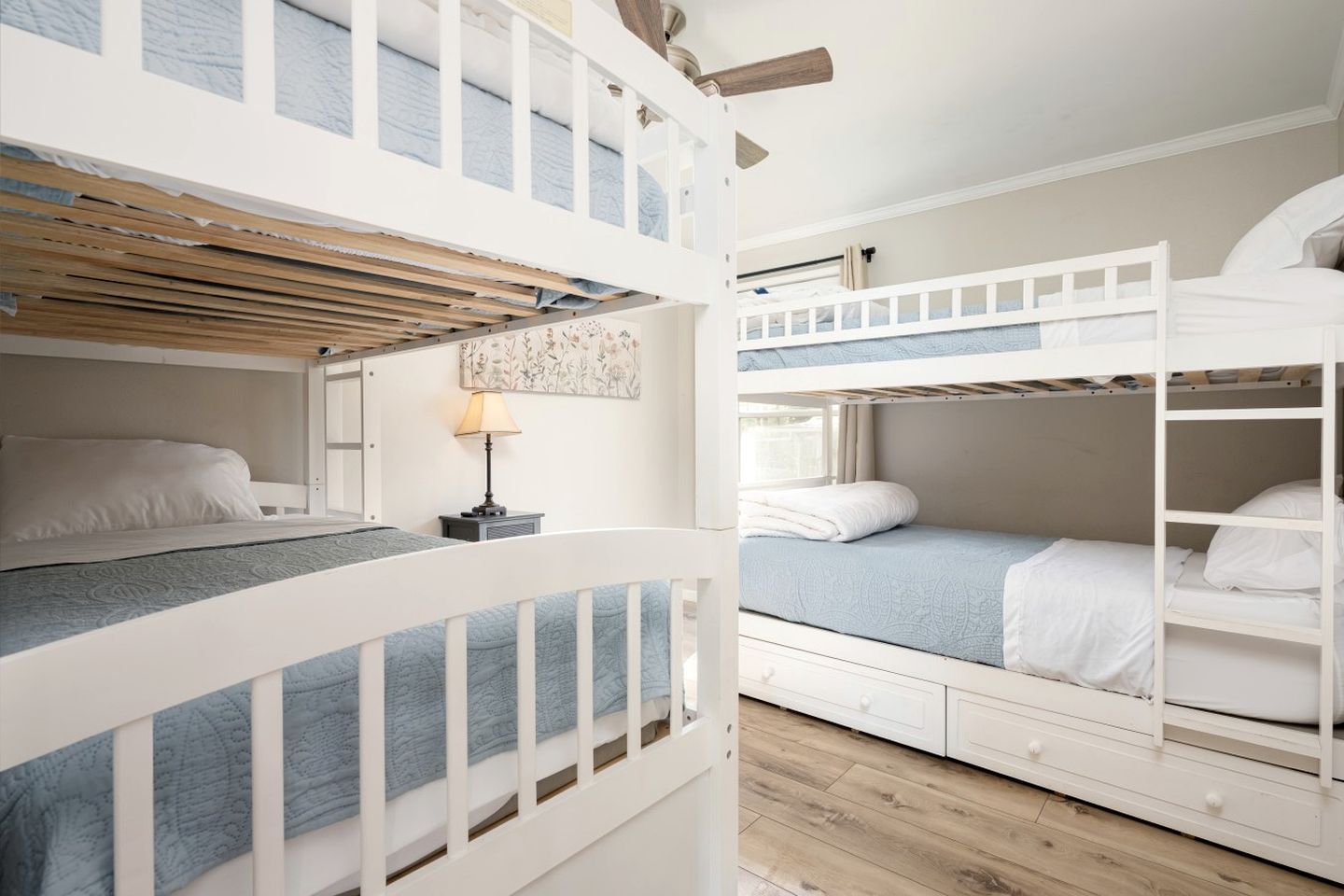 Habitación con literas, techo de madera, una mesita con lámpara y una ventana.