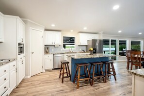 A modern kitchen with white cabinetry, a granite countertop, and a central island with bar stools. - Spacious Vacation Rental with Stunning Lake Views from the Incredible Deck for an Amazing Getaway in Sabine National Forest in Hemphill, Texas (Hemphill)