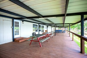 Un'area esterna coperta con tavoli da picnic e panche, un portico coperto e vista sul paesaggio circostante.