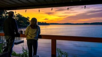 A couple on a wooden deck overlooking a lake at sunset.