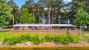 A riverside lodge with a covered deck, surrounded by dense forest.