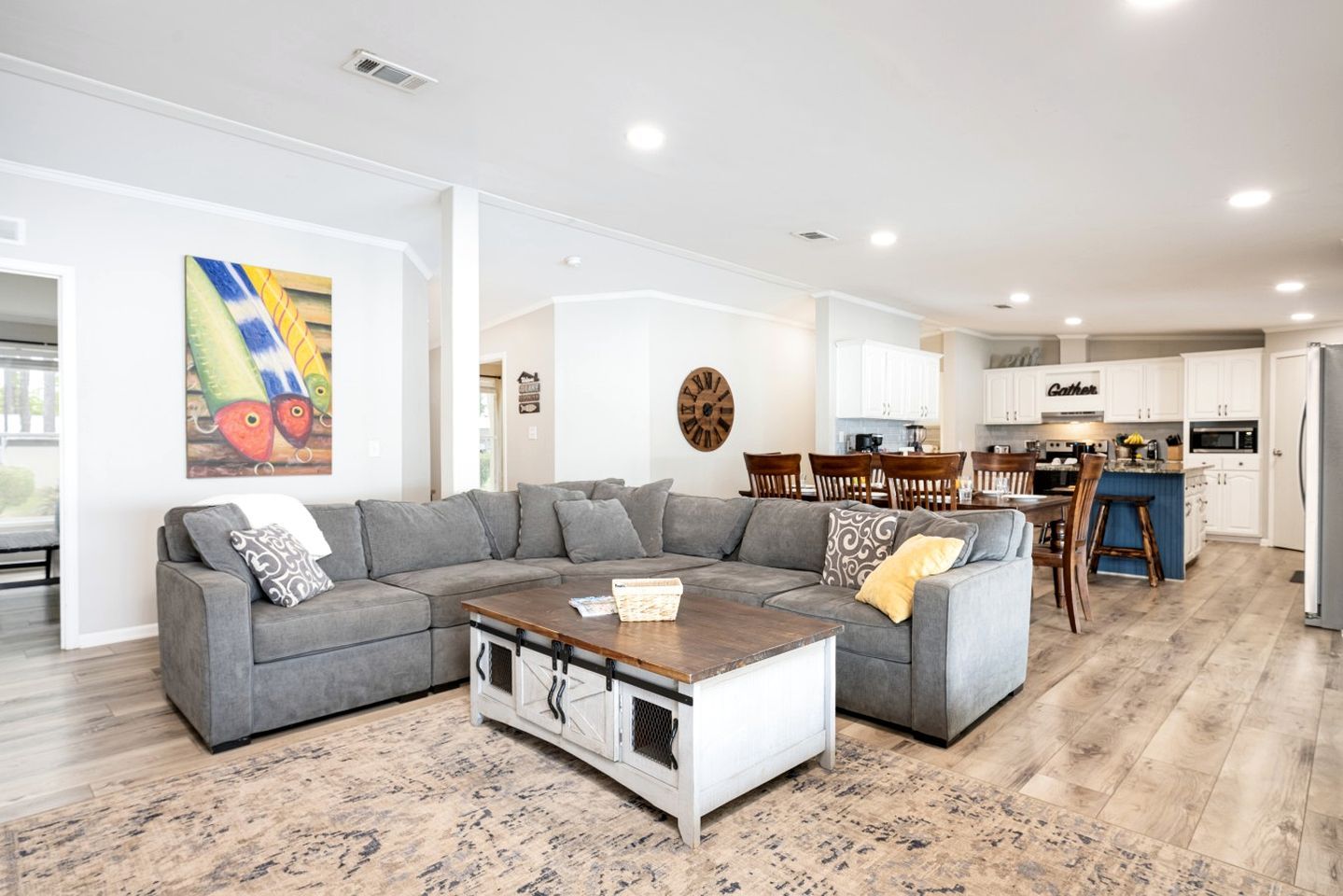 A modern living room with a sectional sofa, a coffee table, and a dining area with wooden chairs.