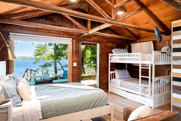 A cabin with a large bed, bunk beds, a desk, and a view of the lake. - Rustic Waterfront Cabin on Toledo Bend Lake for an Unforgettable Getaway in Nature in Hemphill, Texas (Hemphill)