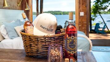 A wicker basket with a Piney Woods Vineyard cap, a bottle of Sangivose Rose wine, and a wine glass on a wooden table.