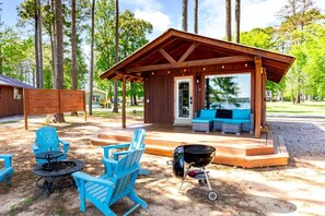 Zona d'estar exterior coberta amb una barbacoa i cadires Adirondack.