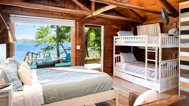 A cabin with a large bed, bunk beds, a desk, and a view of the lake. - Rustic Waterfront Cabin on Toledo Bend Lake for an Unforgettable Getaway in Nature in Hemphill, Texas (Hemphill)