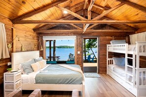 Une cabane avec un intérieur en bois, un lit, un bureau et une vue sur un lac.