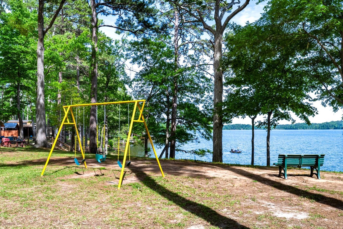 Un parque con un columpio, un banco y un lago.