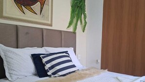 Una cama bien hecha con un cojín a rayas, uno blanco y una manta azul.