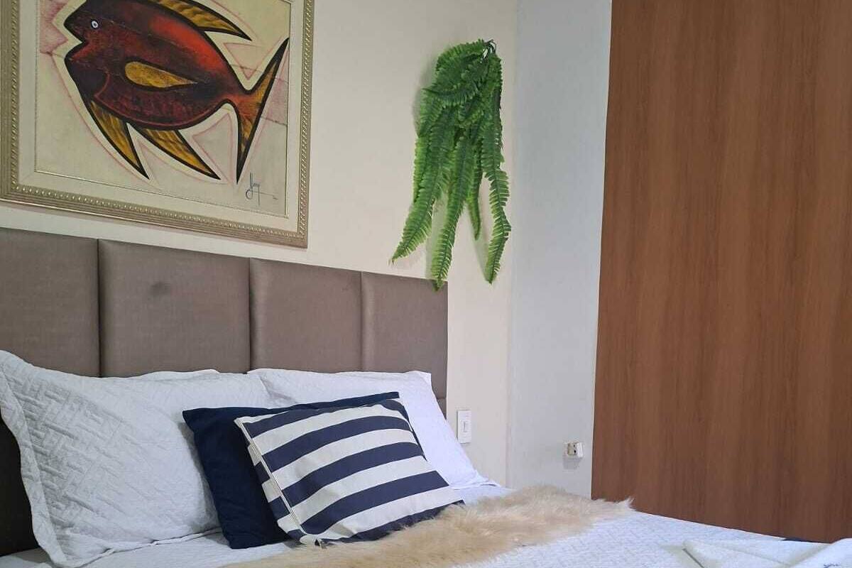 Cama bem arrumada com travesseiro listrado, um travesseiro branco e um cobertor azul.