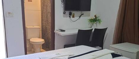 A hotel room with a bed, a desk, a television, a bathroom, and a window.