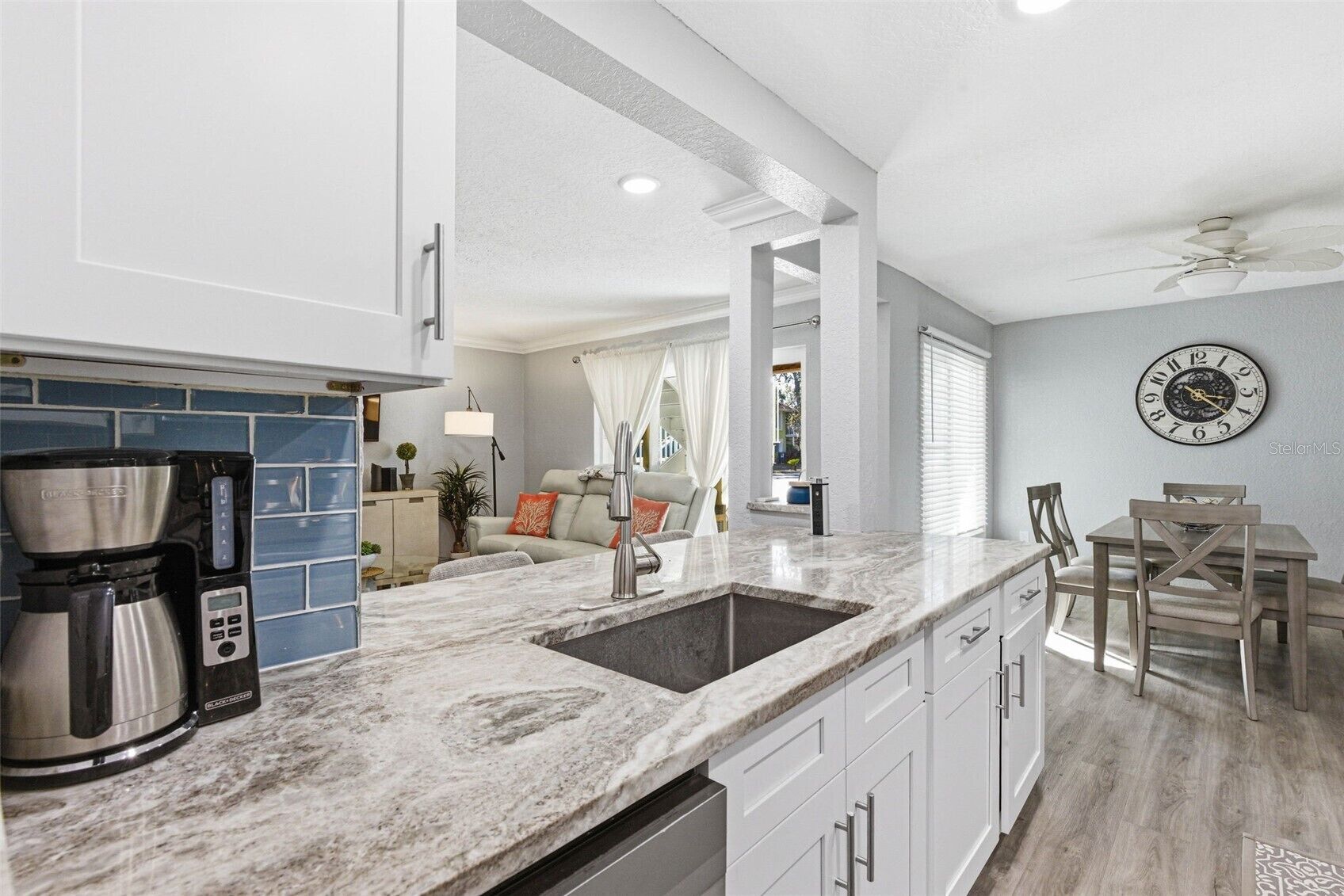 A kitchen with a coffee maker, a sink, and a dining area with a table and chairs.