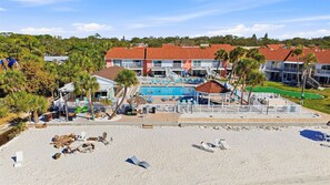 A resort with a swimming pool, beach area, and multiple buildings with red roofs. - Spacious 3BR Condo in Gated St. Petersburg Community with Private Beach (St. Petersburg)