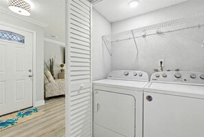 A laundry room with a white wall, a drying rack, and two stacked washing machines. - Spacious 3BR Condo in Gated St. Petersburg Community with Private Beach (St. Petersburg)