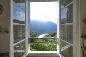 A room with a large window, a door, and a wall-mounted light switch. - Villino Colmenacco - by MyHomeInComo (Nesso)