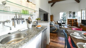 Una cocina con encimeras de granito, un lavamanos de acero inoxidable y una zona de comedor con mesa y sillas de madera.