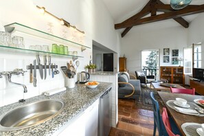 A kitchen with granite countertops, a stainless steel sink, and a dining area with a wooden table and chairs. - Villino Colmenacco - by MyHomeInComo (Nesso)