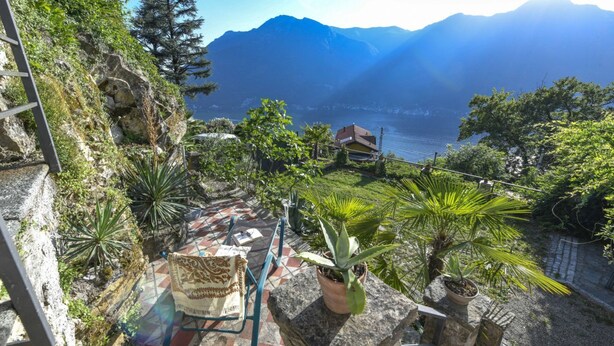 Un paisaje montañoso con vistas a un lago, una casa y una escalera de piedra.