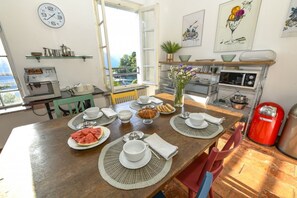 A dining area with a wooden table set for breakfast, a coffee machine, and a view of the outdoors. - Villino Colmenacco - by MyHomeInComo (Nesso)