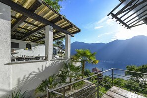 Ein Küstengebäude mit Außenbereich, einer Treppe und Blick auf Meer und Berge.