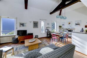 Ein Wohnzimmer mit Fernseher, einer Couch und einem Essbereich mit Stühlen und Tisch.