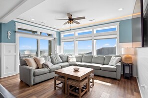 Ein modernes Wohnzimmer mit einem Ecksofa, einem Holztisch und einem Deckenventilator.