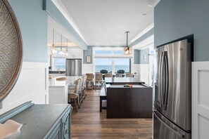 A modern kitchen with a large island, stainless steel appliances, and a view to the ocean. - Sea-Batical: a 9-bedroom: Priv. Pool w Opt. Heat, Hot Tub, Oceanfront (Oak Island)