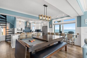 A modern kitchen with a pool table, dining area, and a view of the ocean. - Sea-Batical: a 9-bedroom: Priv. Pool w Opt. Heat, Hot Tub, Oceanfront (Oak Island)