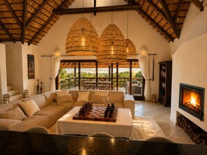Un salón espacioso con chimenea, un tablero de ajedrez y un balcón con vistas.
