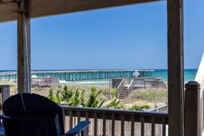 A wooden deck with a view of a pier extending into the ocean. - Whit's End: Oceanfront, Private Pool, Elevator, Hot Tub, Theater and Game Room (Nags Head)