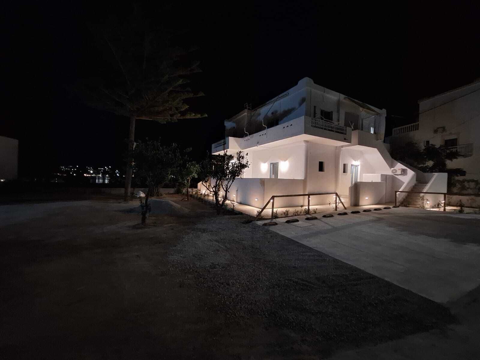 A modern building with a flat roof, a staircase leading to the entrance, and a well-lit exterior.