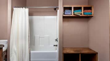 Une salle de bain avec un rideau de douche, une baignoire et une étagère où sont pliées des serviettes.