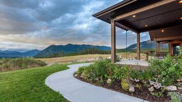 A building with a covered patio, a curved pathway, and a mountainous backdrop.