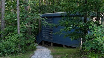 A gravel path leading to a blue structure surrounded by trees.