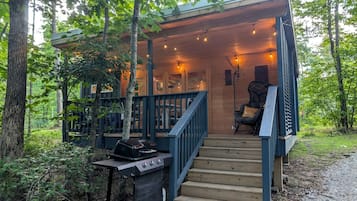 Une terrasse en bois avec un barbecue, une chaise et un escalier menant à un niveau supérieur.