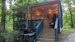Eine Holzterrasse mit Grill, einem Stuhl und einer Treppe zu einer erhöhten Ebene.
