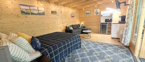 A wooden interior with a bed, sofa, and kitchenette.