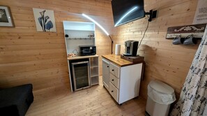 Eine kleine Küche mit Mikrowelle, Kaffeemaschine und einem Kühlschrank.