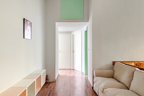 A hallway with a sofa, a framed picture, and a green door. - Milano Lambrate Station | Metro M2 | 2-Bedroom Apartment (Milan)