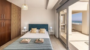 A bedroom with a bed, bedside tables, a hanging light, a view of the sea, and a balcony. - 3 Bedroom Penthouse In the Absolute Center Of Protaras (Paralimni)