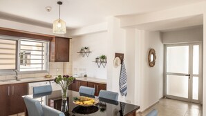 A modern kitchen with a dining area, a large window, and a door leading to a balcony. - 3 Bedroom Penthouse In the Absolute Center Of Protaras (Paralimni)
