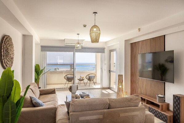 Ein modernes Wohnzimmer mit Sofa, Fernseher und einem Balkon mit Aussicht.