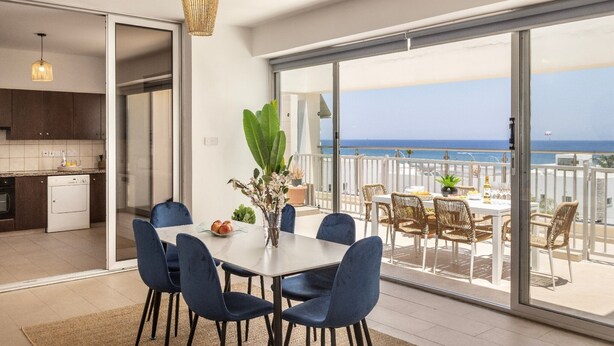 Eine moderne Küche mit Geschirrspüler, ein Essbereich mit Tisch und Stühlen sowie ein Balkon mit Meerblick.